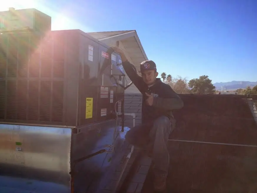 HVAC technician performing Boiler Repair on a rooftop unit in Geneseo